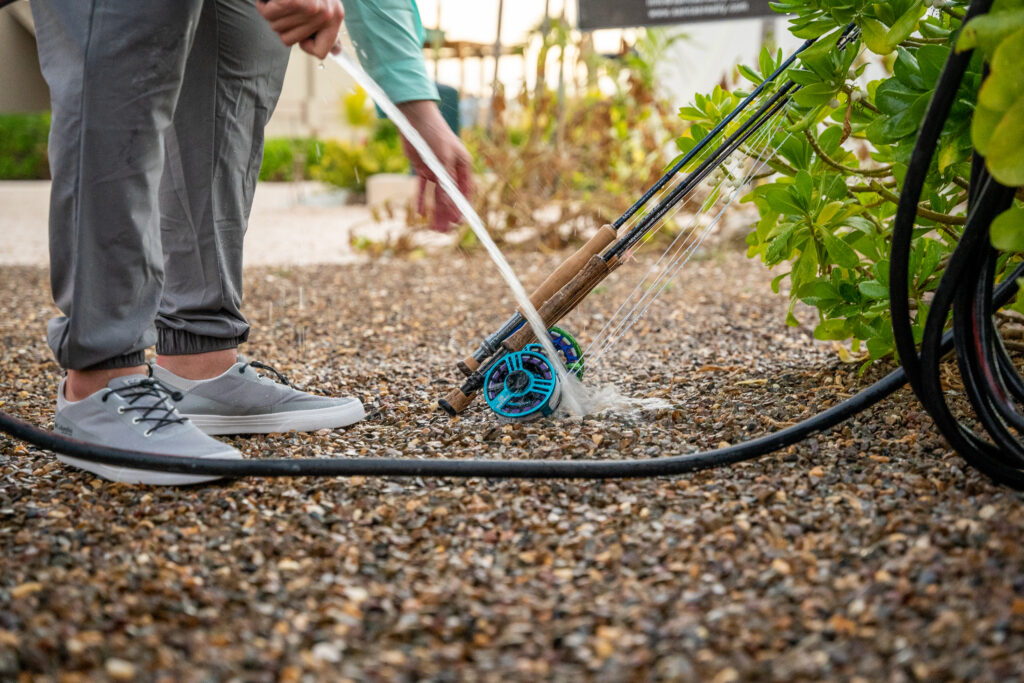 A fly fisherman cleaning his fly fishing line with a cloth, carefully wiping away dirt and debris. Keeping the line clean is essential for maintaining its performance, preventing wear, 